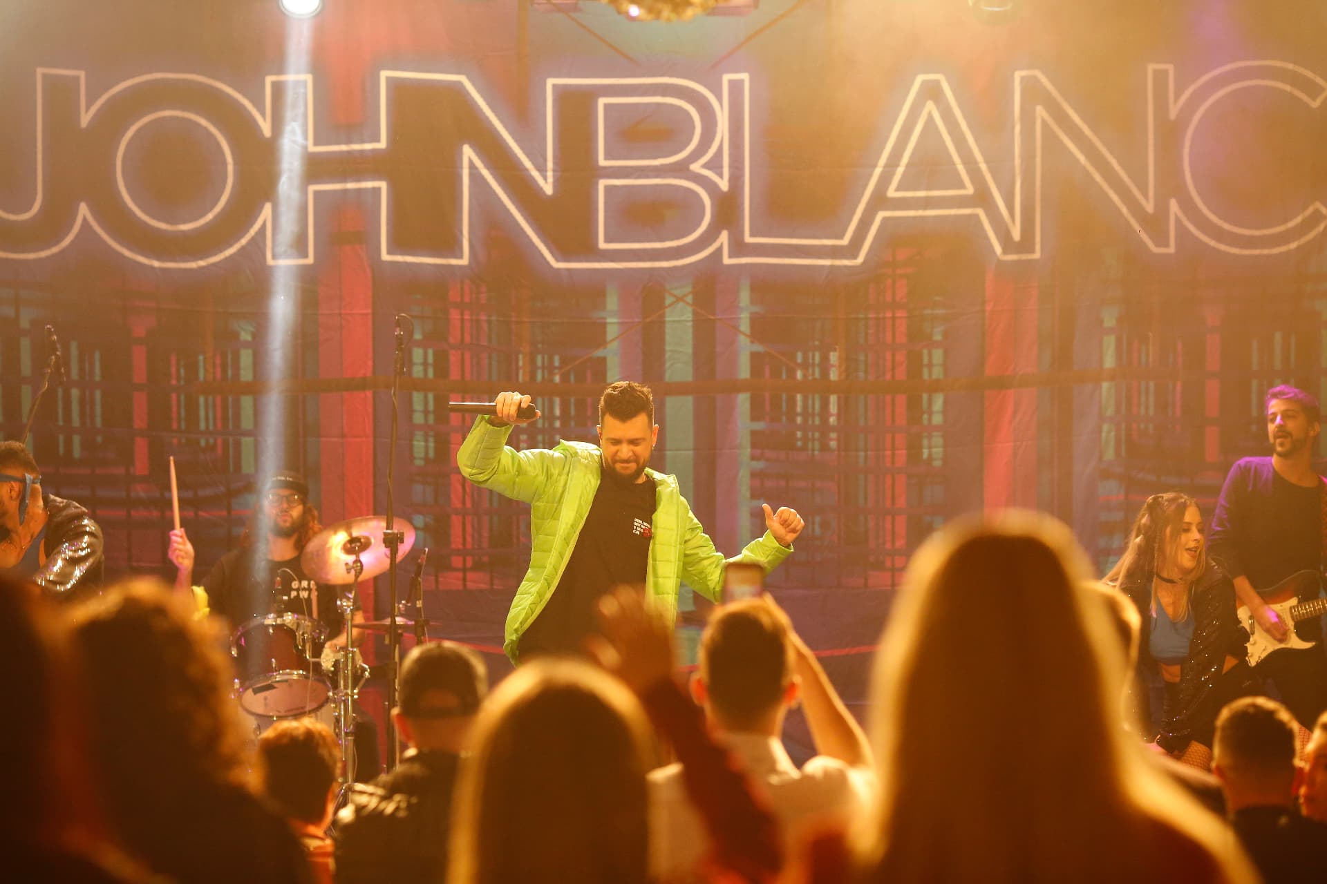John Blanc cantando em um grande palco diante do público